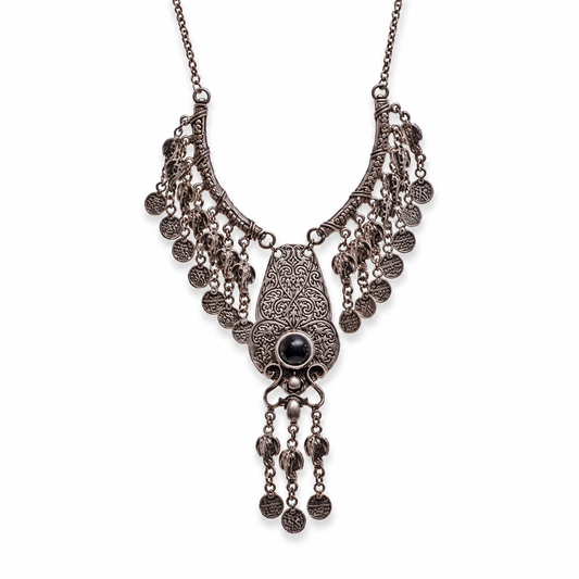 Silver-tone necklace with an ornate filigree pendant, red stone center, and coin fringe.