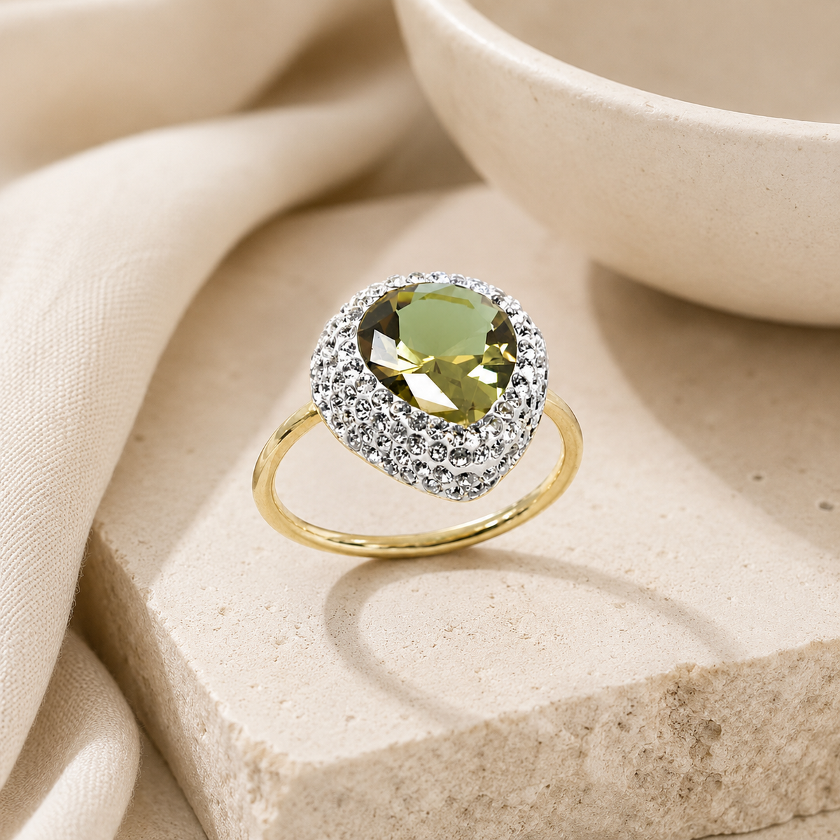 Gold-tone ring with a heart-shaped green stone on a white background.