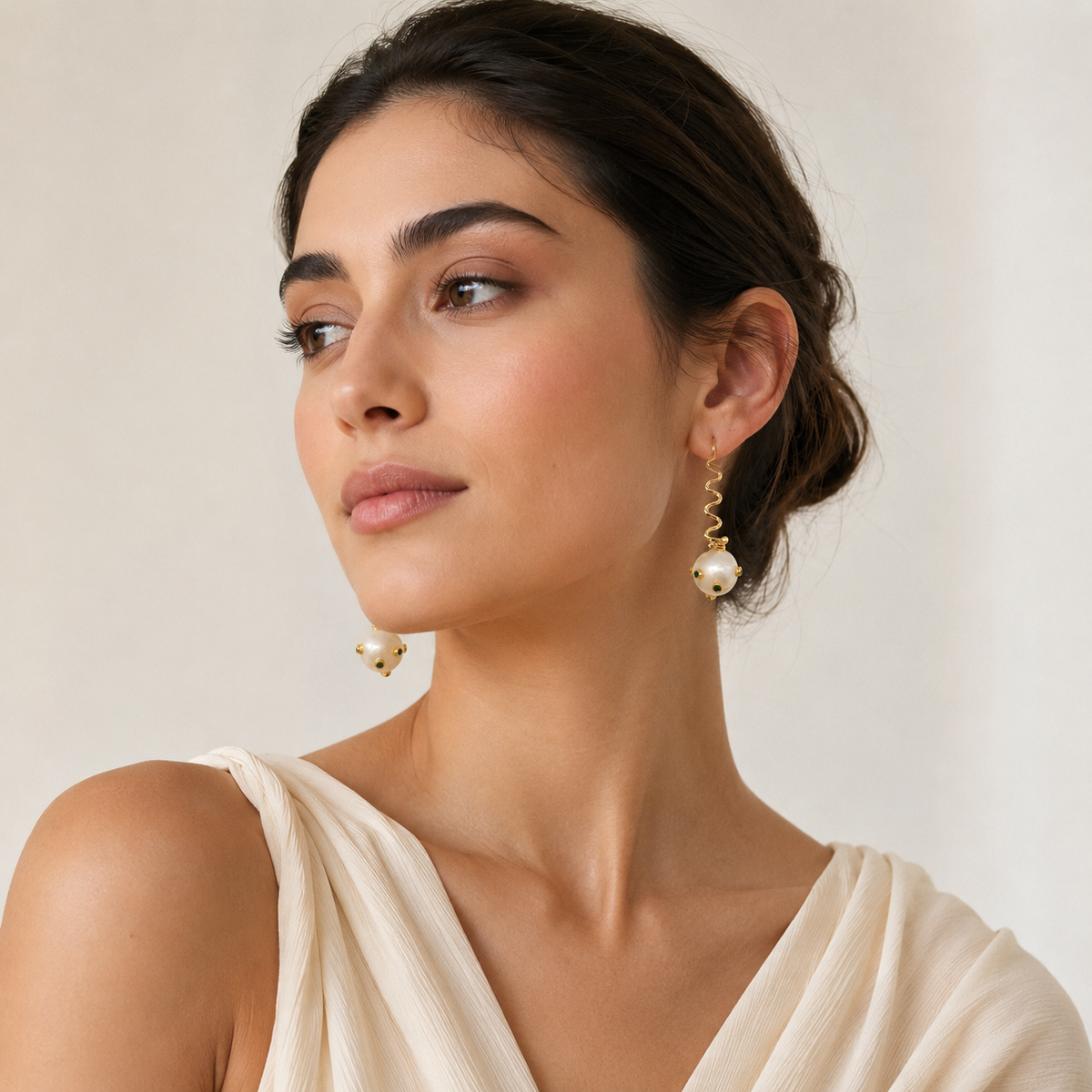 Pair of sculptural drop earrings with pearl-like balls and gold-tone finish.
