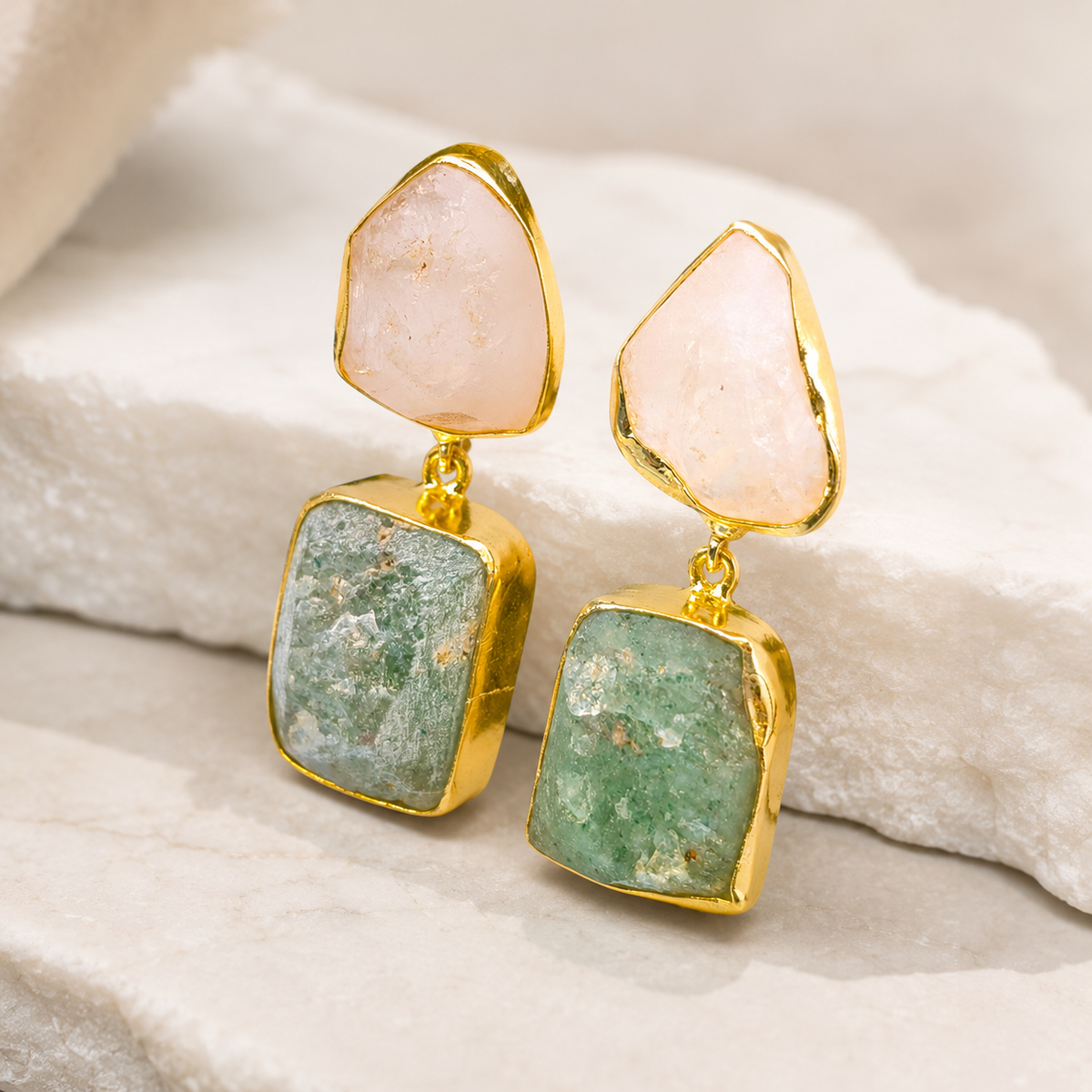 Angle view of gold plated earrings with rough rose quartz and apatite stones.
