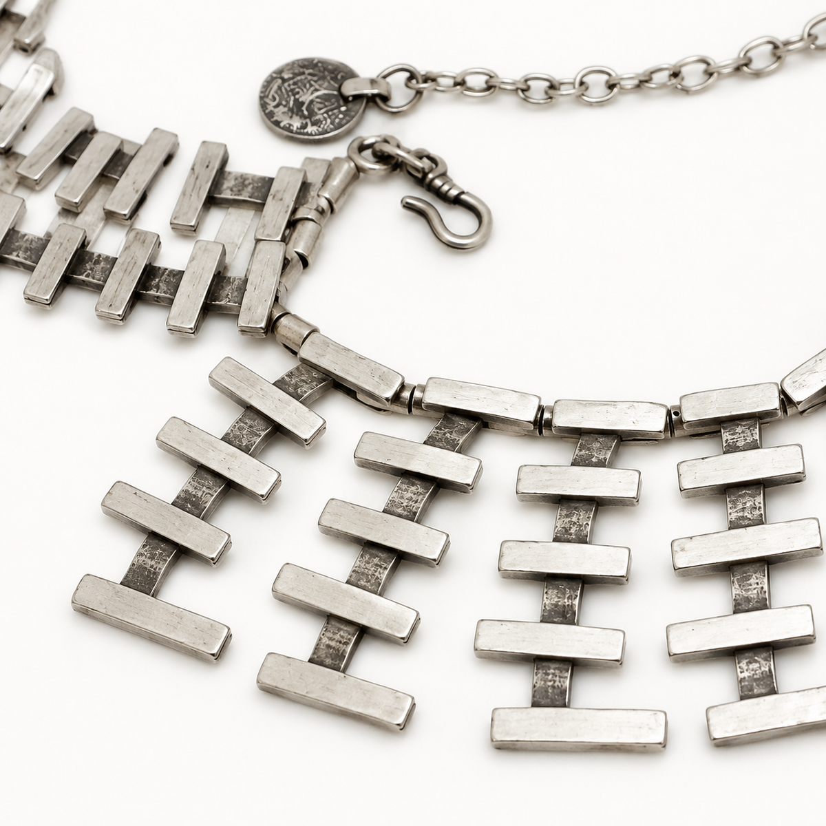 Close view of the silver-tone bars and collar links on the necklace.