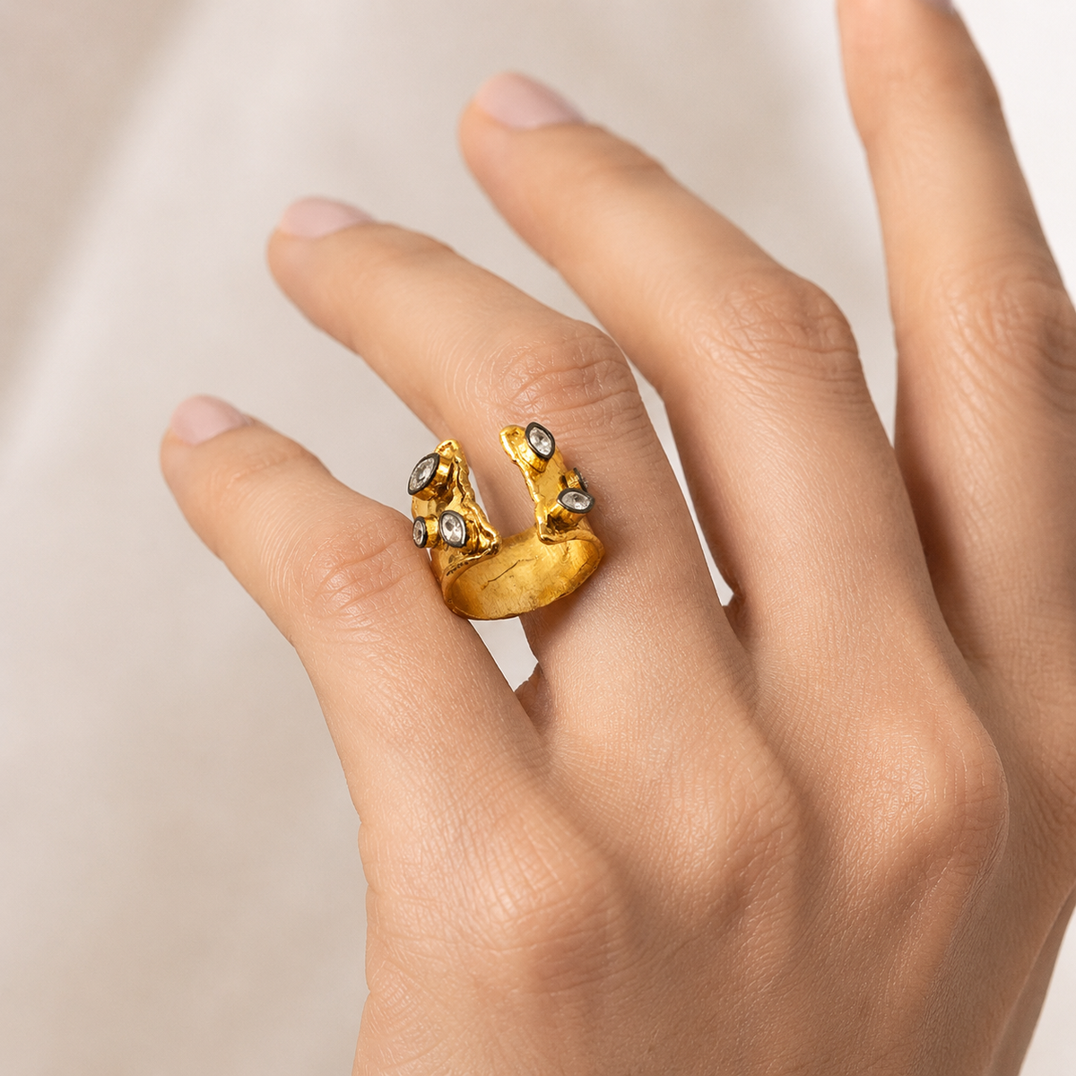 Gold-plated open cuff ring with clear quartz accents shown from a close angle.