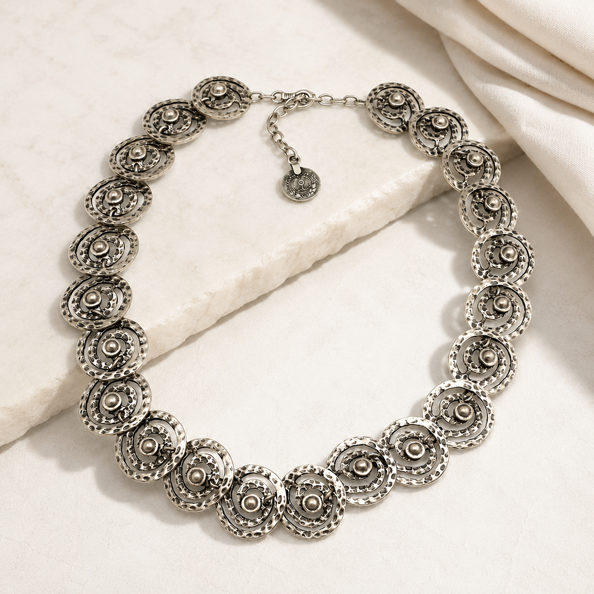 Silver-tone necklace with spiral disc links arranged in a statement silhouette.