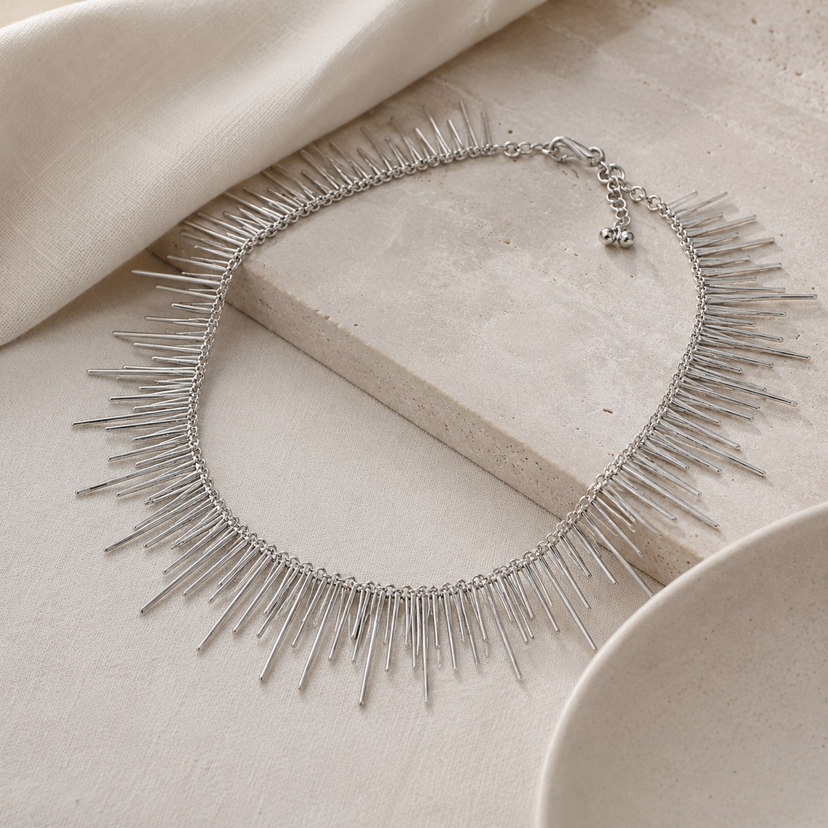Angled view of a silver-tone collar necklace with long spike details.