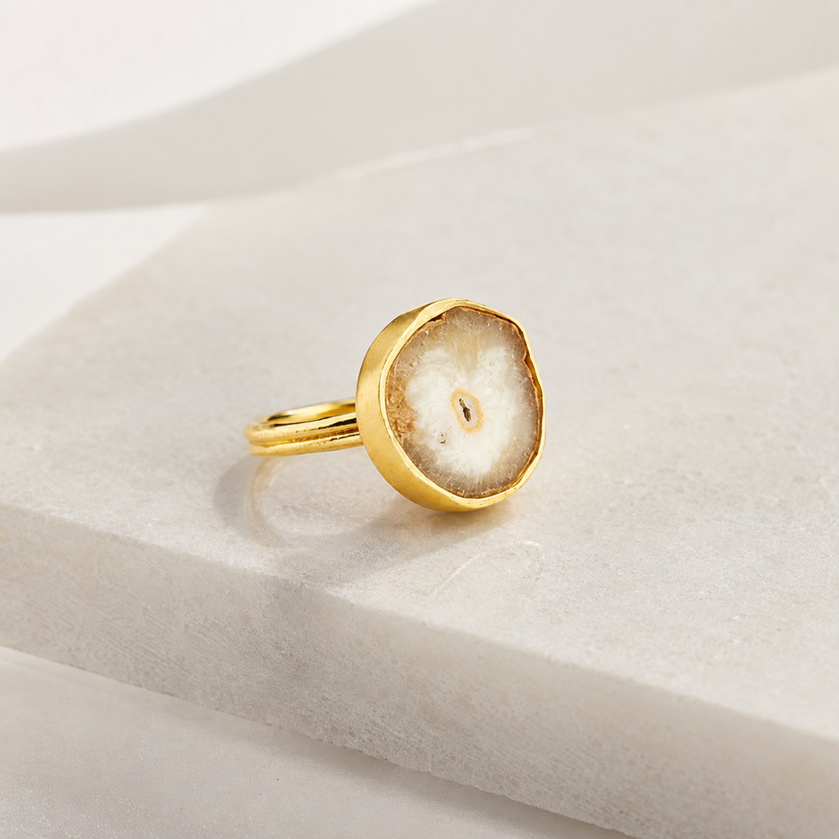 Angled view of a gold-plated bezel ring with a natural quartz slice.