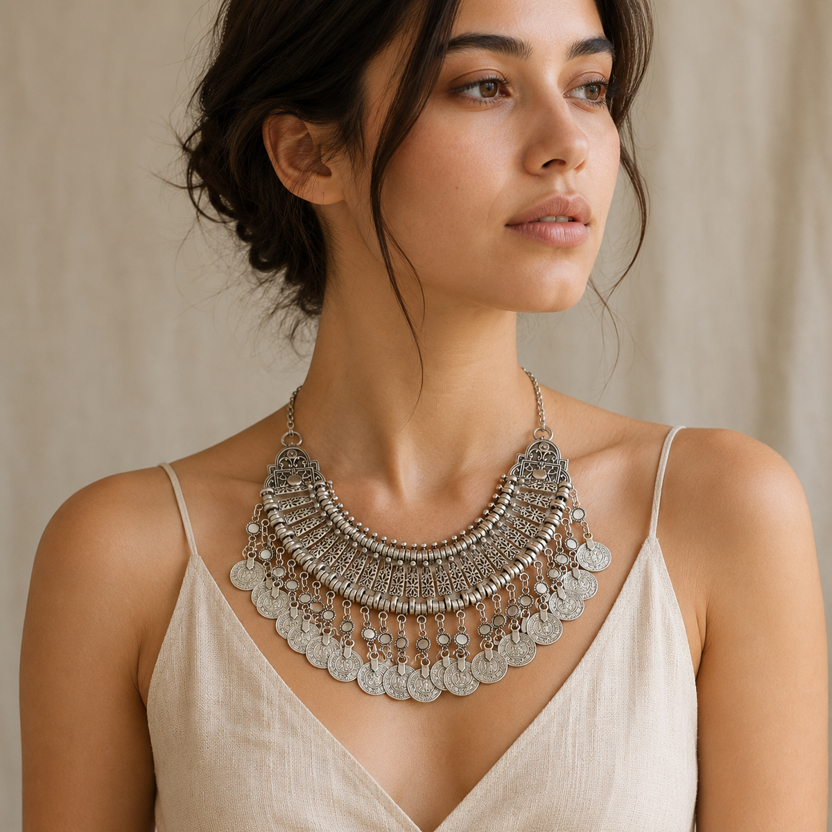 Decorative silver-tone statement necklace with ornate cutout panels and fringe coins.