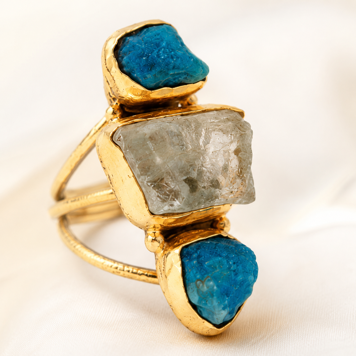 Close view of the three-stone ring with textured blue and clear stones.