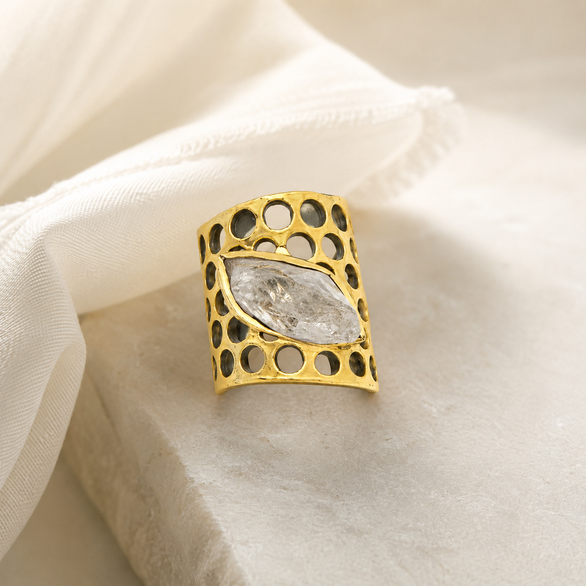 Statement ring with clear quartz and a sculptural gold-plated finish.