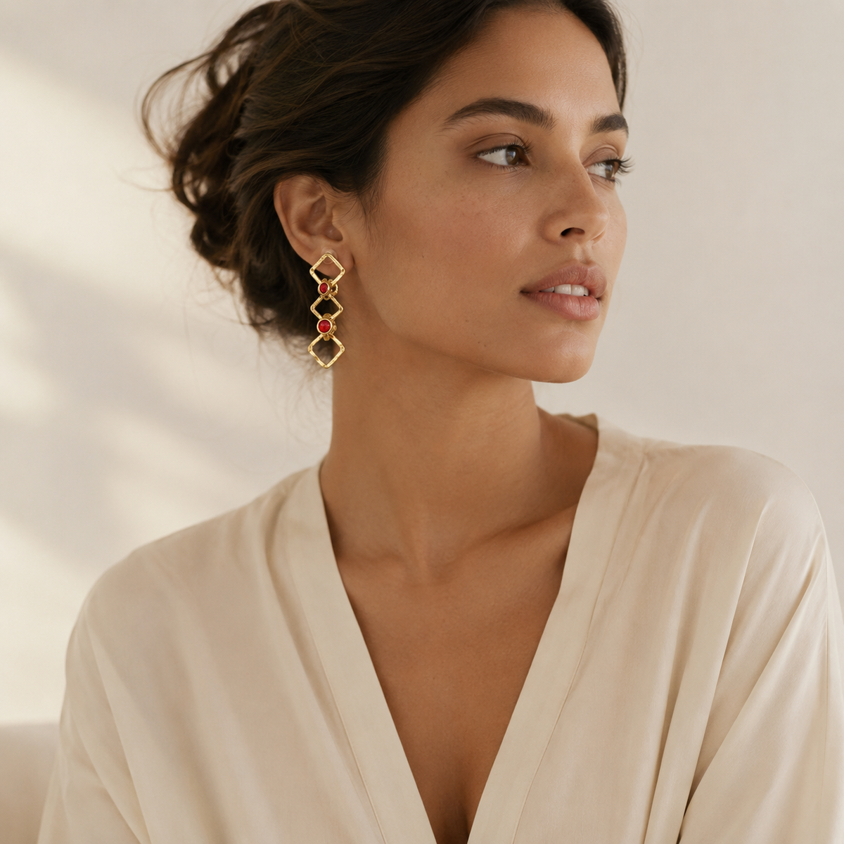 Gold-tone geometric drop earrings with linked shapes and red stone details.