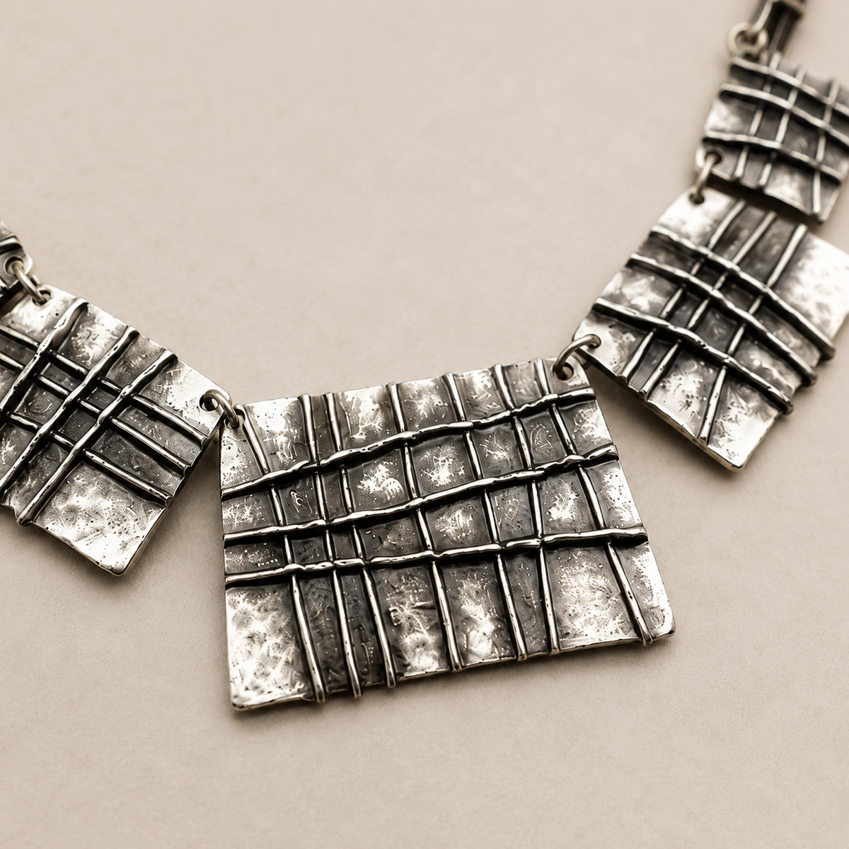 Close view of the grid-textured plaque details on the necklace.