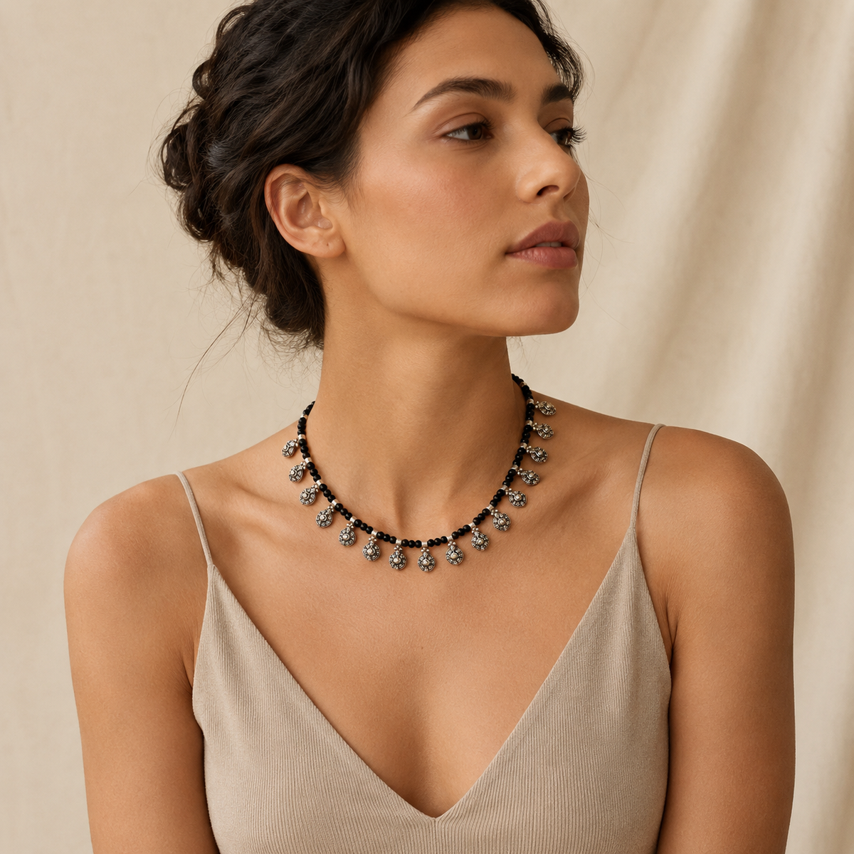 Black bead necklace with silver-tone oval charms shown from the front.