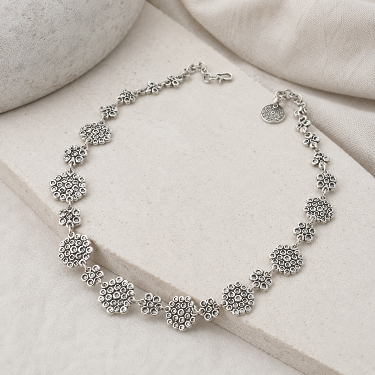 Angle view of a silver-tone linked heart-inspired statement necklace.