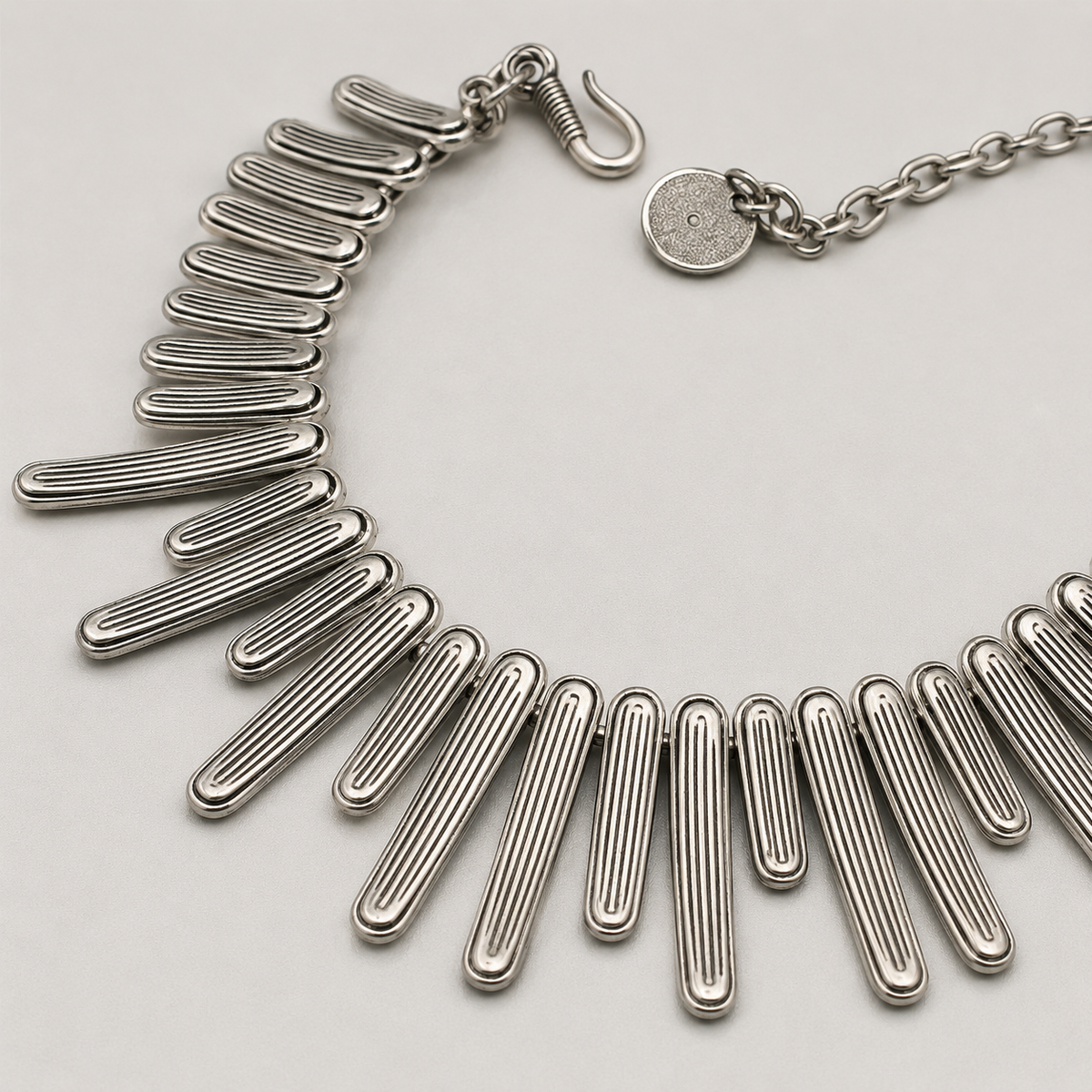 Close view of the silver-tone bar details and chain clasp.