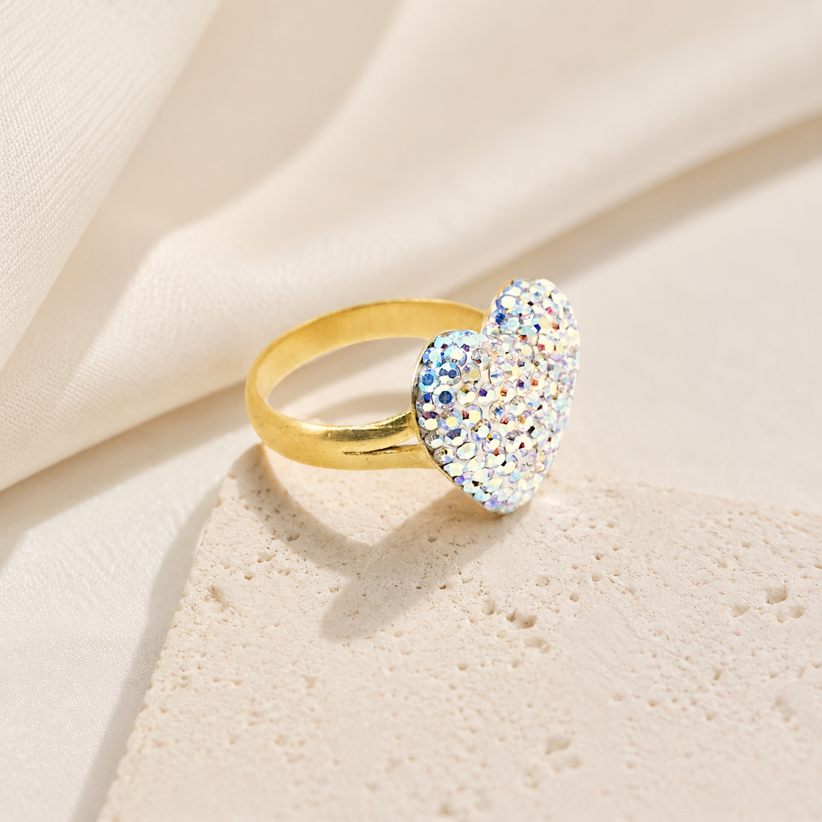 A sparkling heart ring with a gold-plated band on a white background.