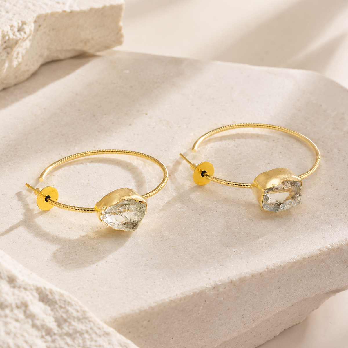 Angled view of yellow solar quartz earrings with gold-plated hooks.