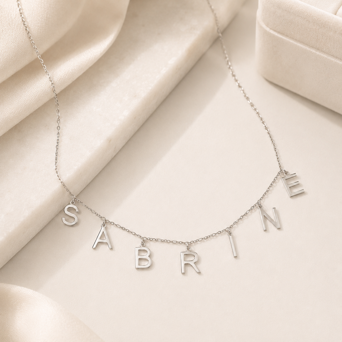 Personalized letter necklace with a soft silver-tone finish and light chain silhouette.