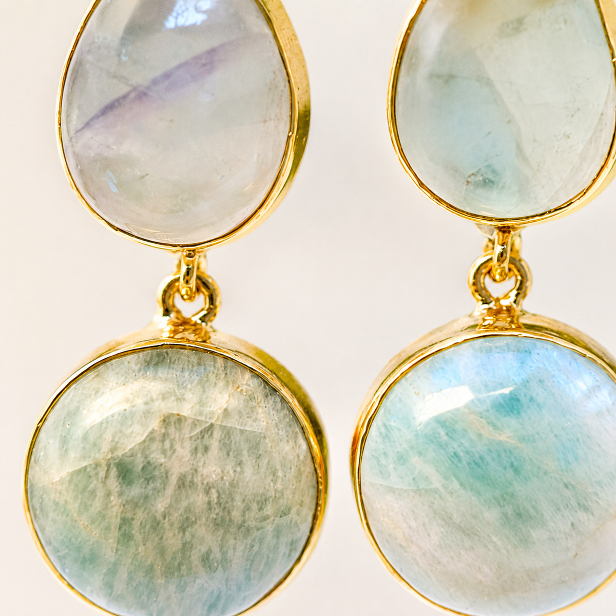 Close view of the two-stone drop earrings with polished gold-tone edges.