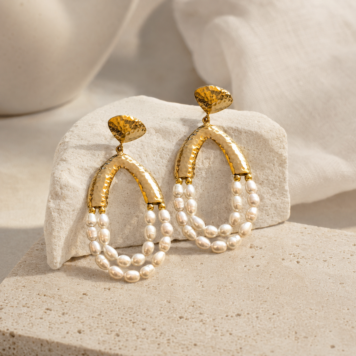 Gold-tone chandelier earrings with layered pearl drops shown on a white background.