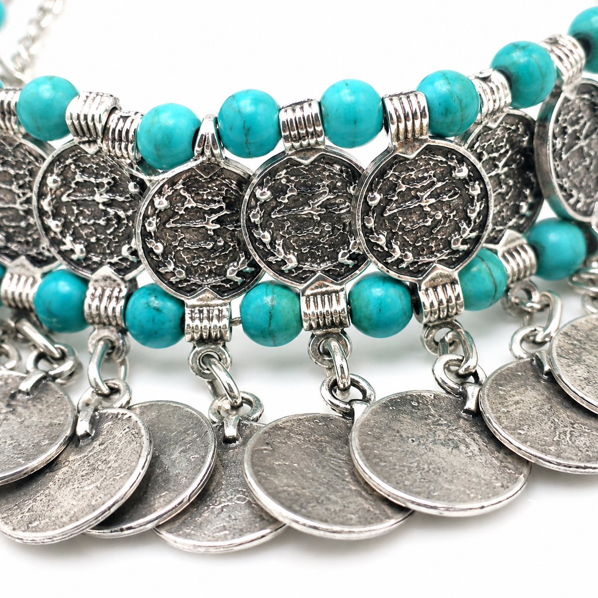 Close view of turquoise beads and textured silver-tone coin charms.