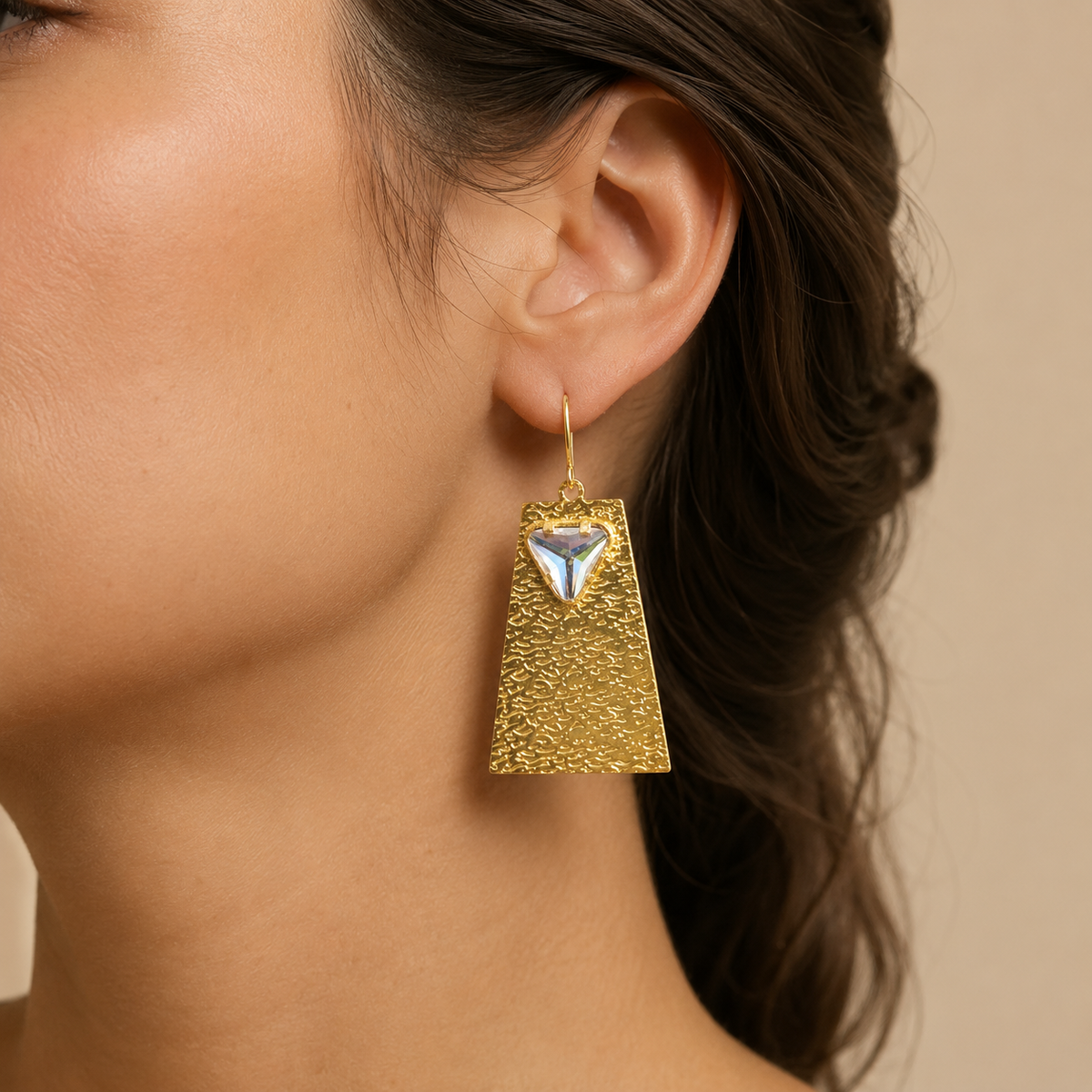 Gold geometric drop earrings with a clear crystal accent shown from the front.
