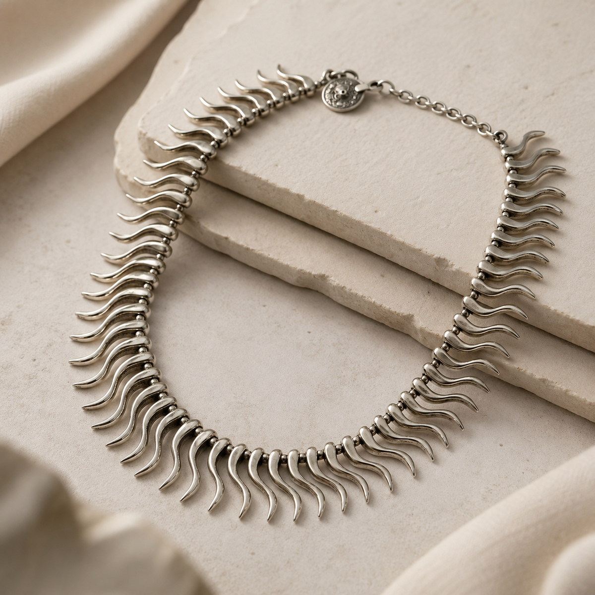 Angled view of a silver-tone curved spike collar necklace with a sleek profile.