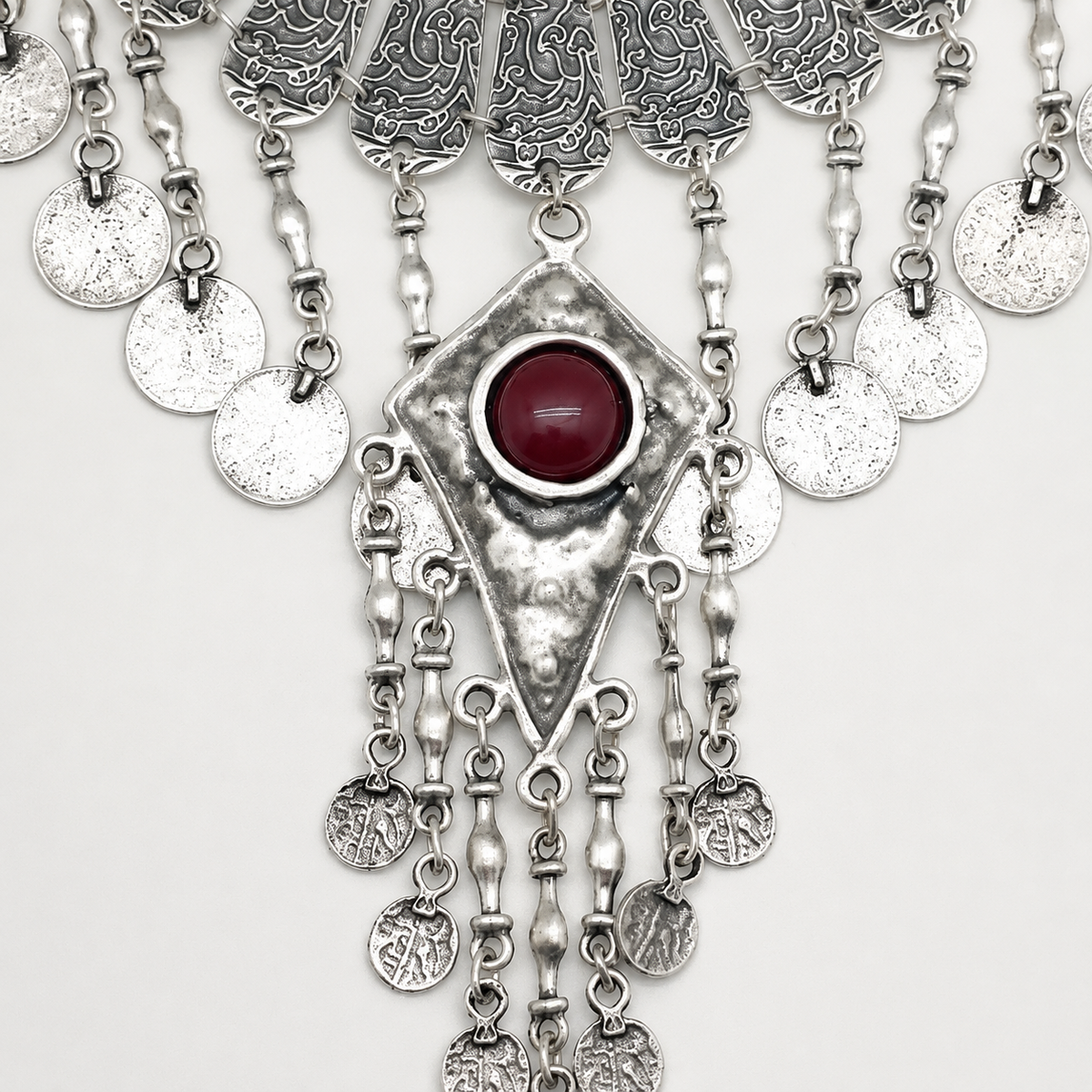 Close view of the necklace’s textured silver-tone coins and center pendant.