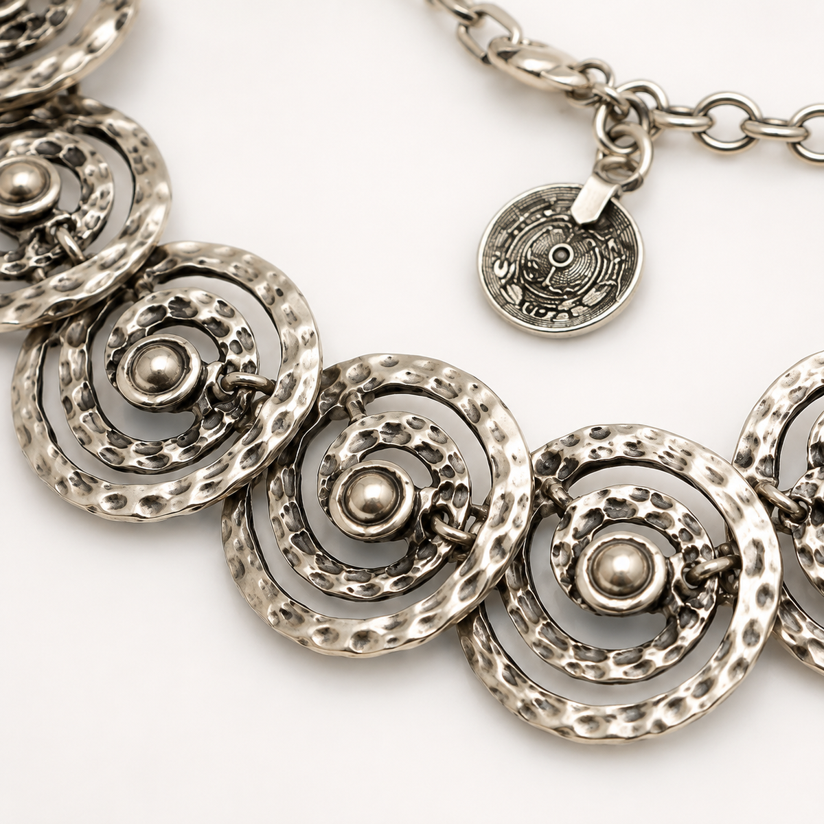 Close view of the necklace’s textured spiral disc links and polished finish.