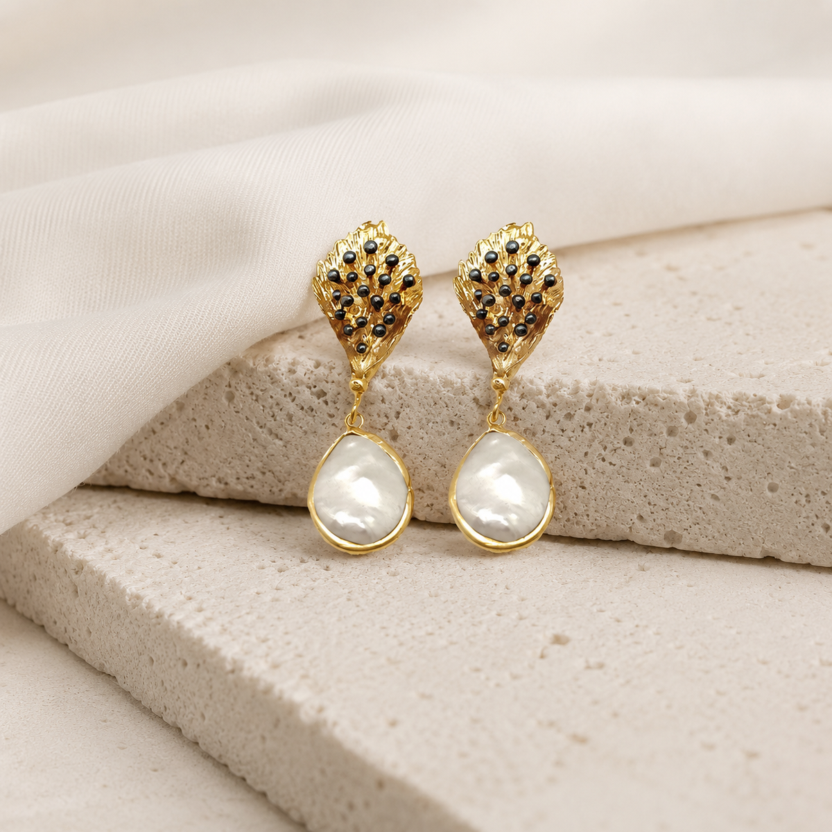 Gold-tone statement drop earrings with a pearl-like lower drop.