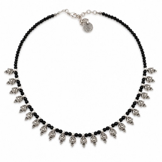 Black bead necklace with silver-tone dangle accents on a white background.