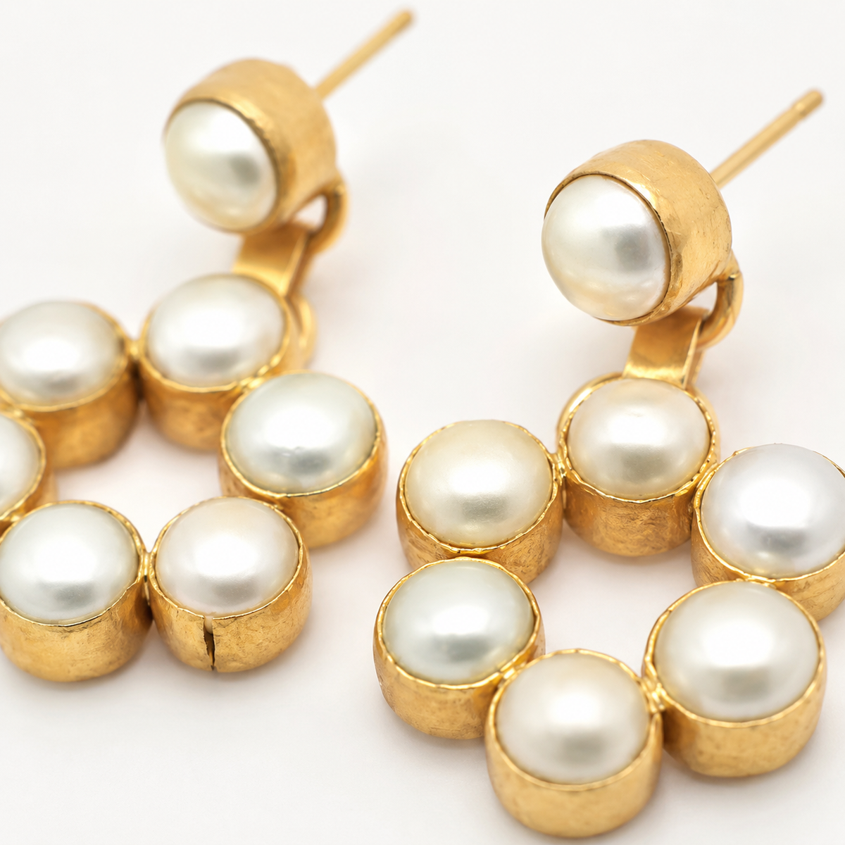 Close view of round pearl accents set in gold-plated earrings.