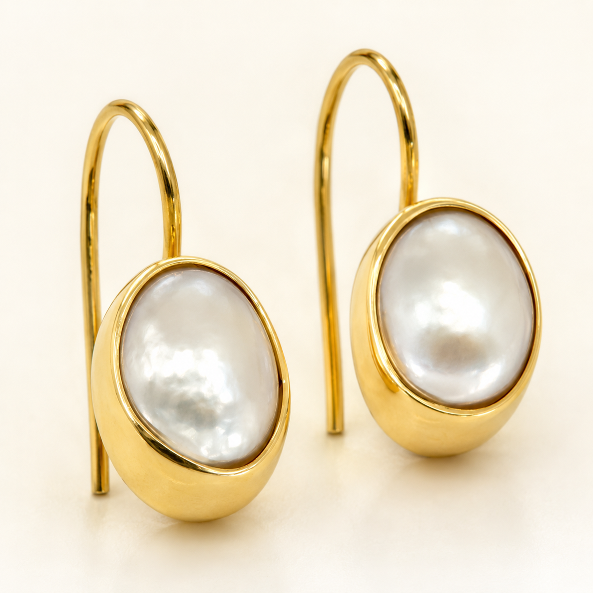 Close view of mother of pearl square drop earrings with a gold-plated frame.