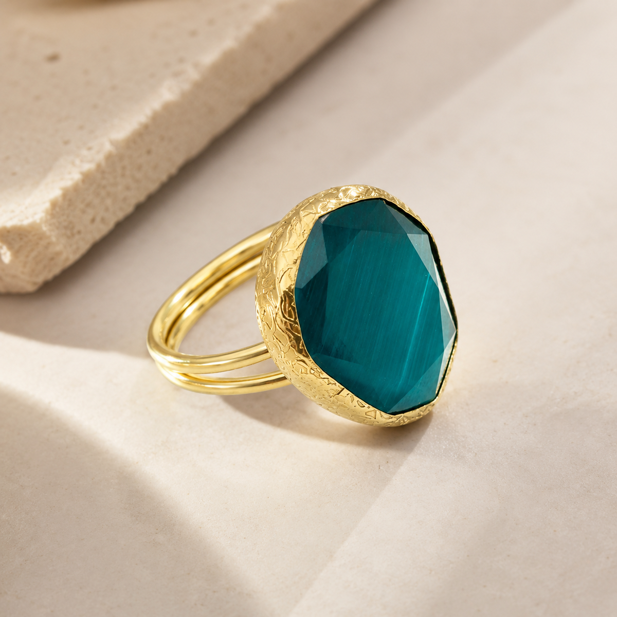 Angled view of a gold-tone ring with a faceted green stone.
