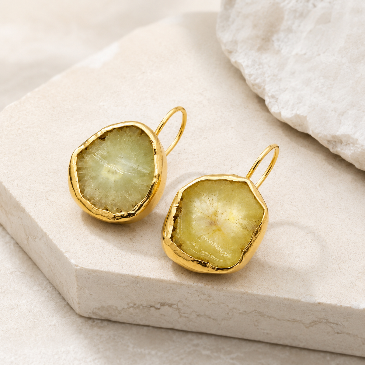 Angle view of raw garnet hoop earrings with softly irregular gold-plated frames.