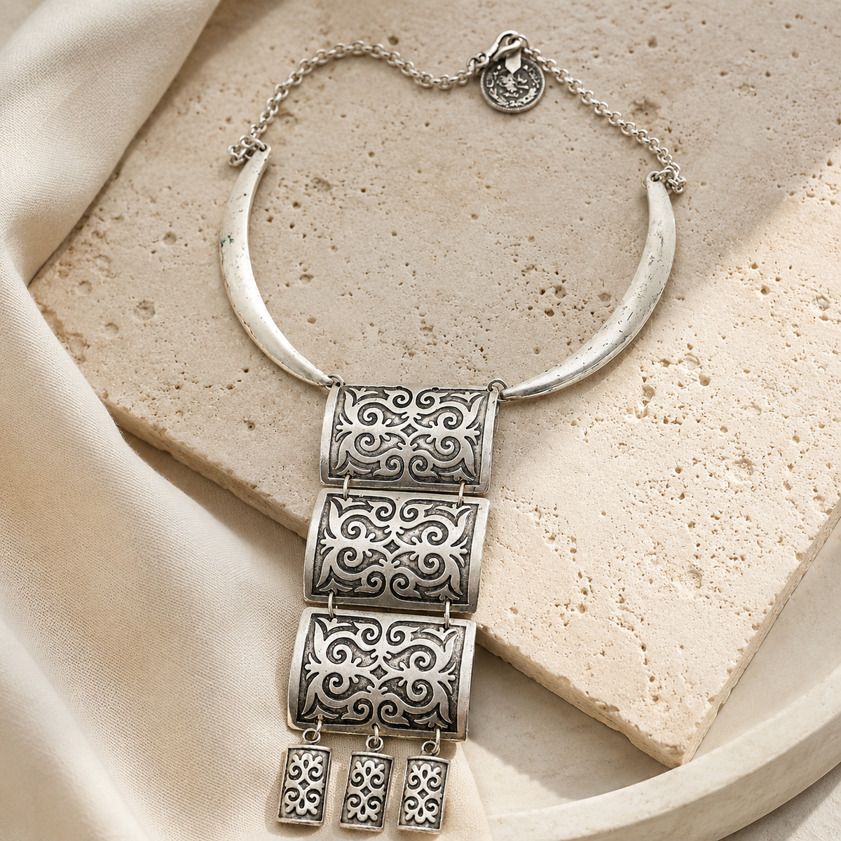 Silver-tone fringe necklace with a bold layered pendant silhouette.