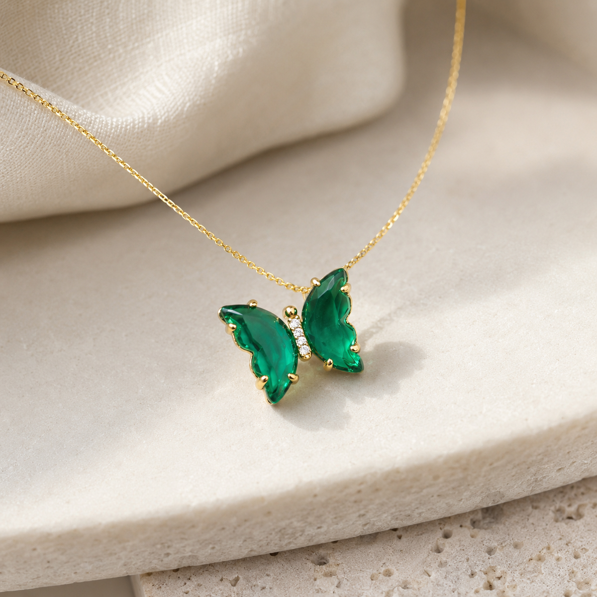 Angle view of a green butterfly pendant necklace with a gold-tone chain.