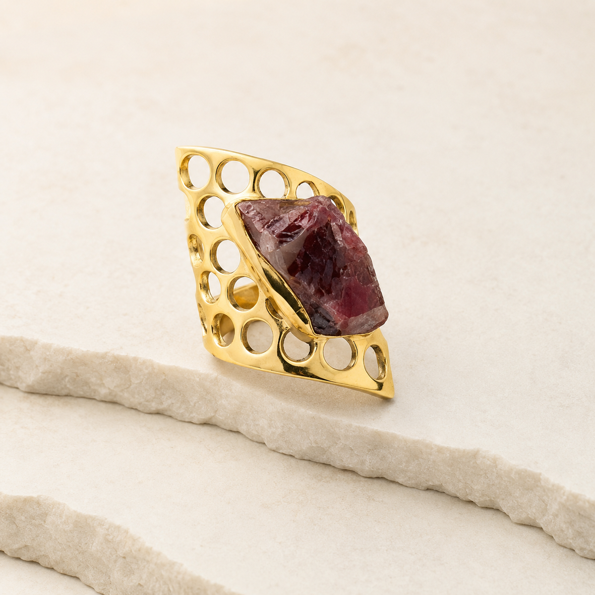 Side angle of a gold-plated statement ring with a raw garnet stone.