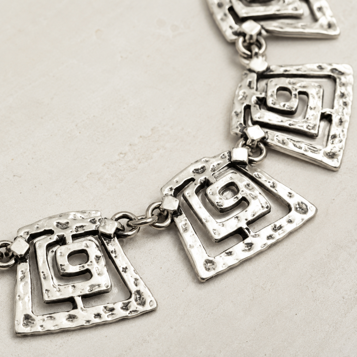 Close view of the spiral square link details and polished silver-tone finish.