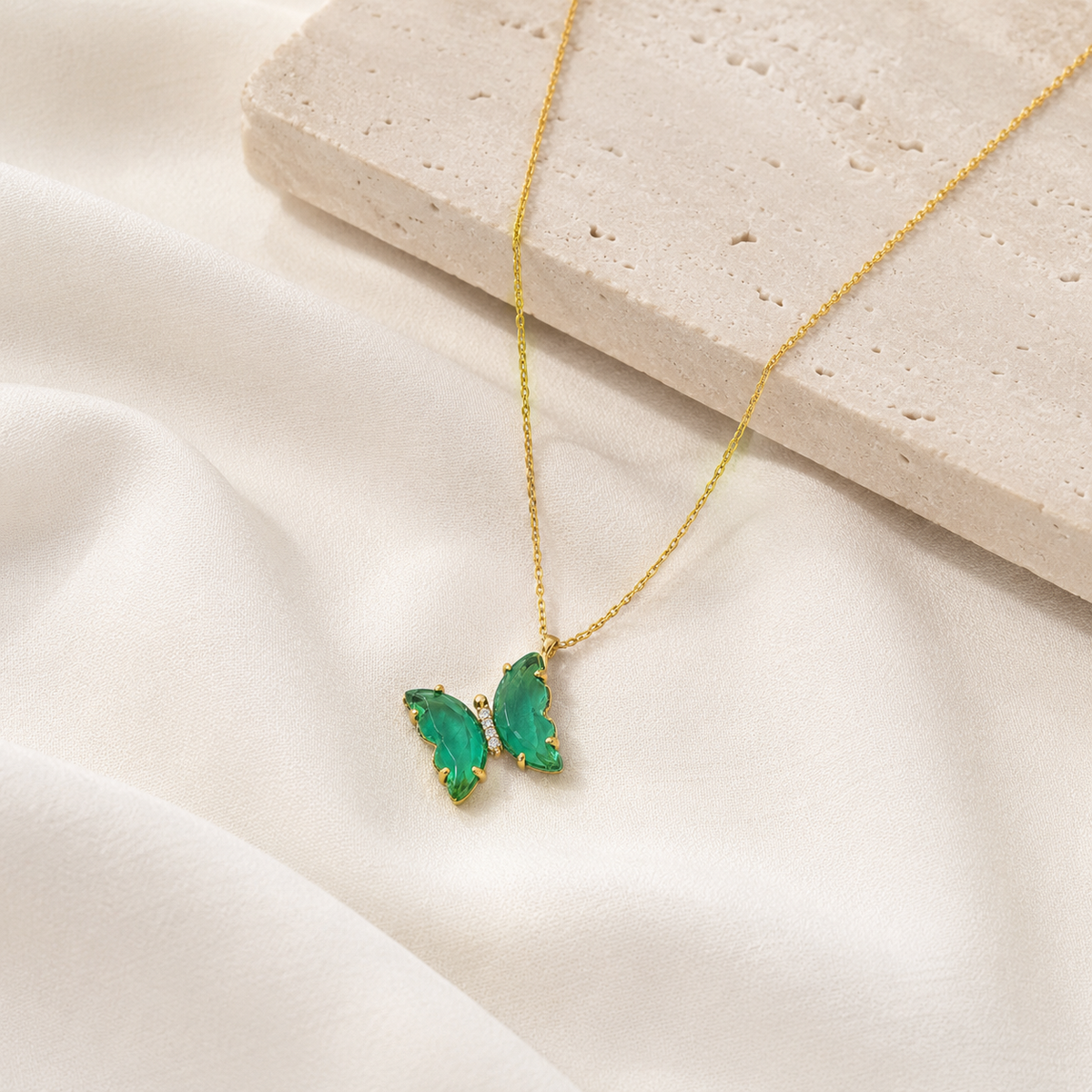 Green butterfly pendant necklace styled as a simple statement piece.
