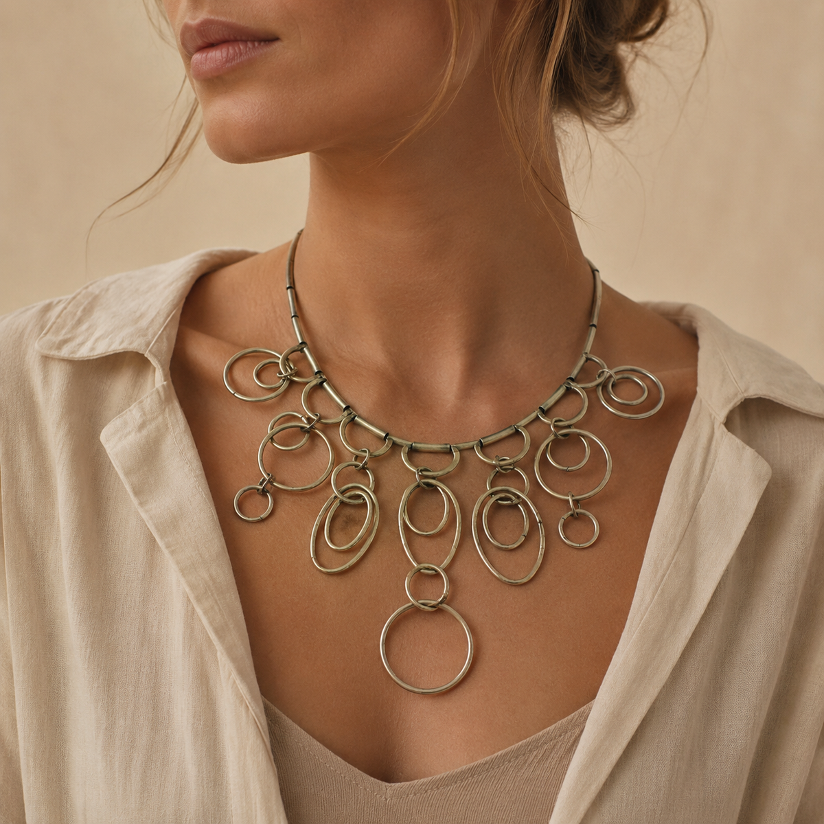 Silver-tone statement necklace with layered ring drops and a sculptural silhouette.