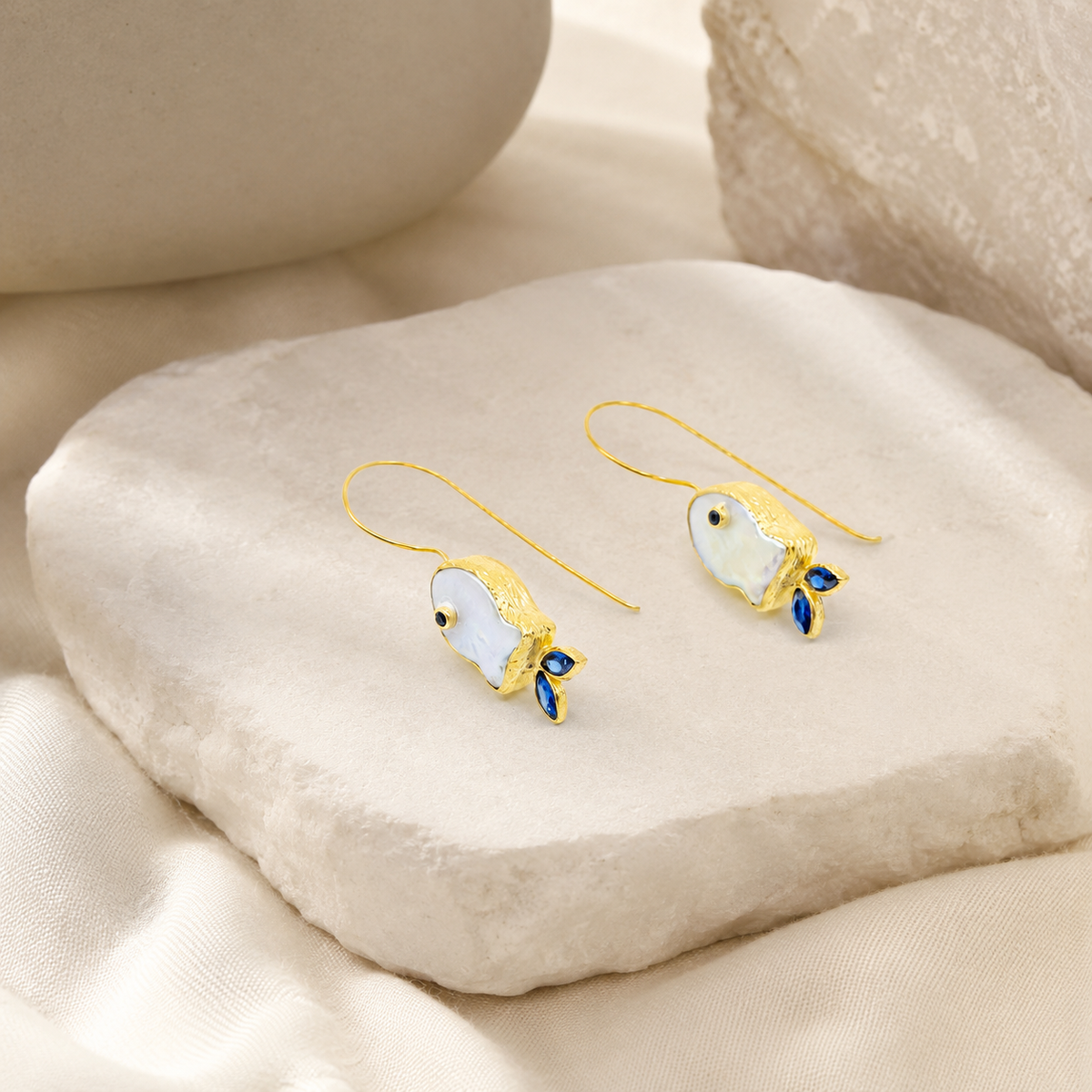 Pair of gold-plated drop earrings with a pearl-like fish shape and blue accents.
