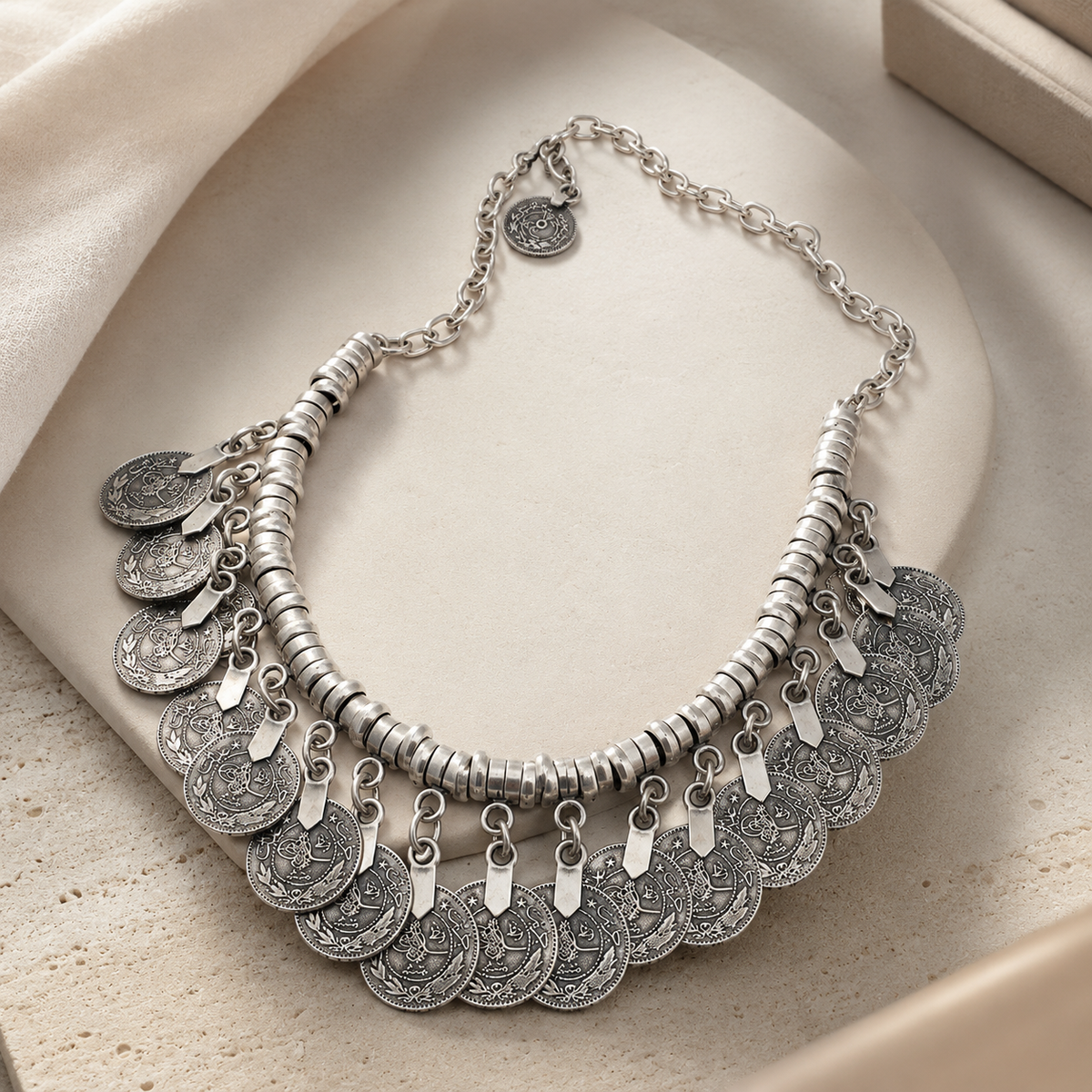 Angled view of a silver-tone collar necklace with disc coin fringe.