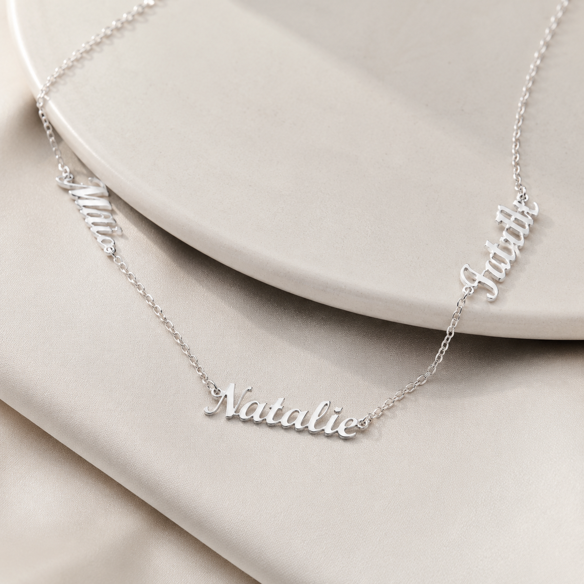 Angle view of a personalized three name necklace with a fine chain.