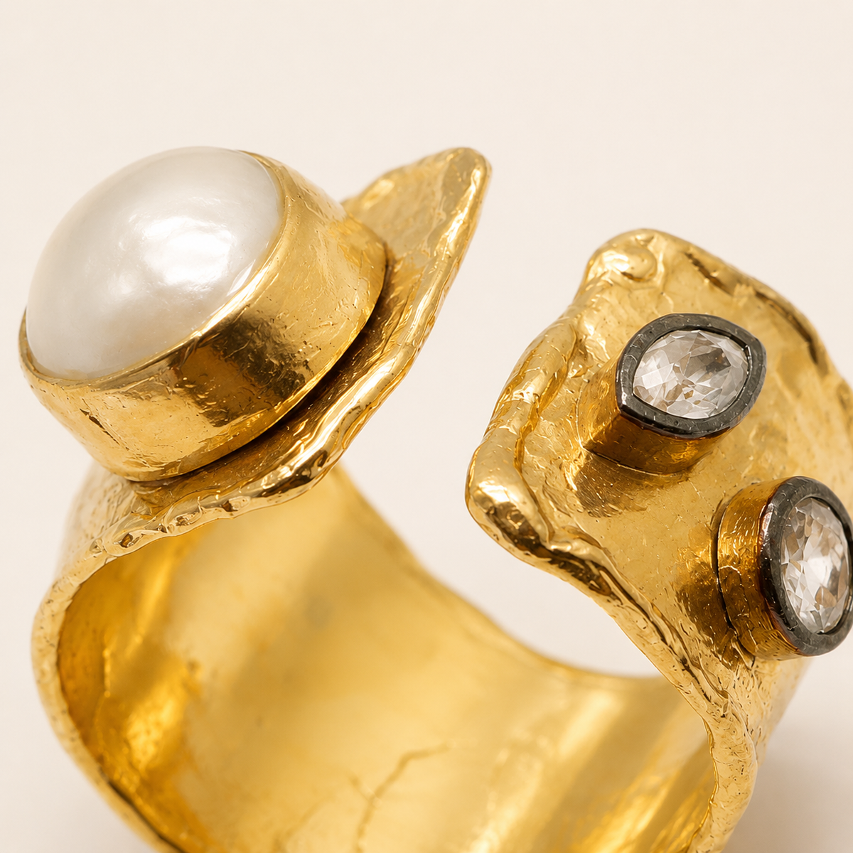 Side angle of a gold-plated ring with sculptural texture and clear CZ accents.
