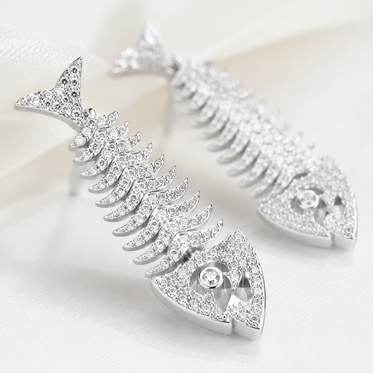 Close view of silver fish bone earrings with textured CZ detail.