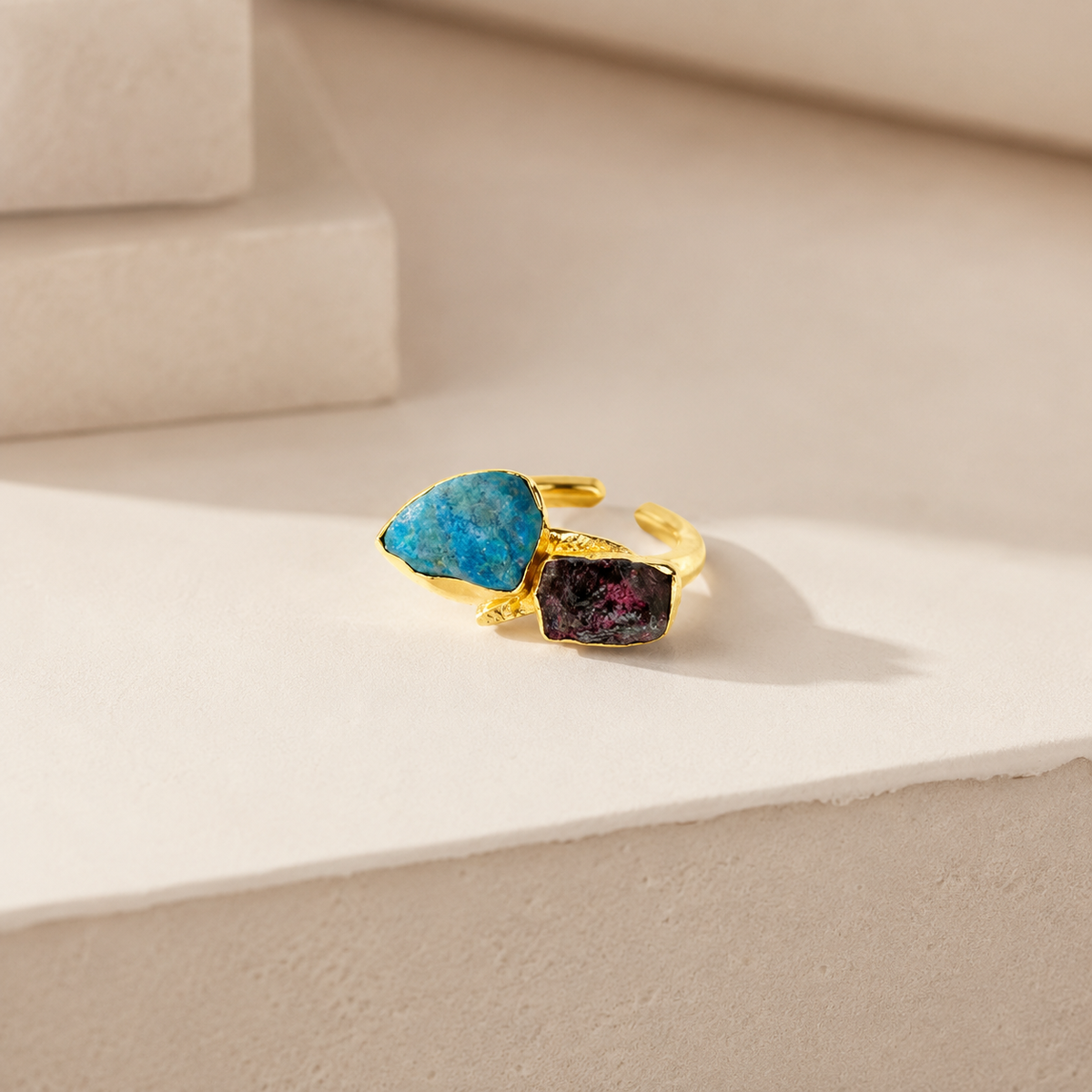 Angled view of a two-stone gold-plated ring with raw apatite and garnet.