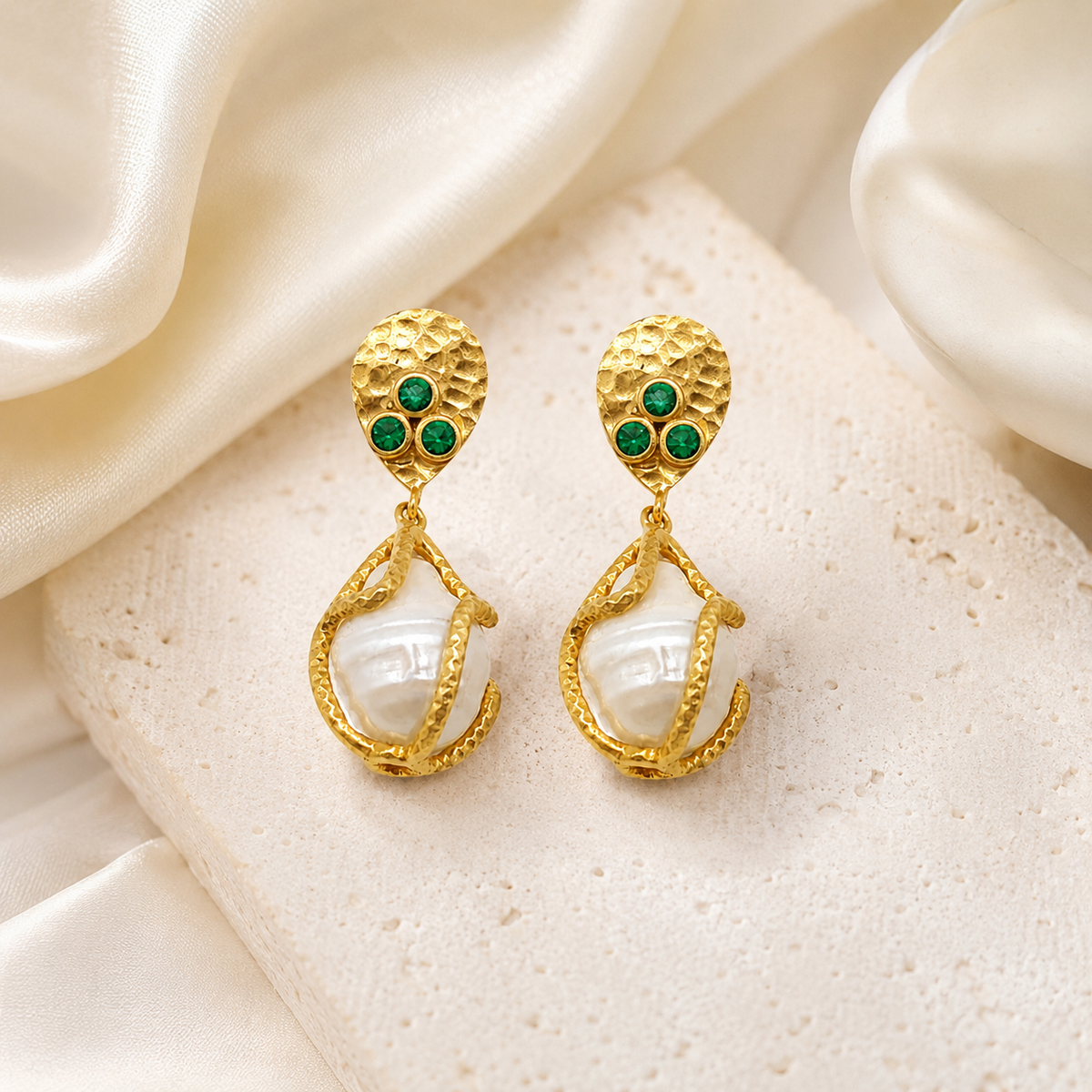 Textured gold-plated earrings with green CZ accents and a pearl-like center on a white background.