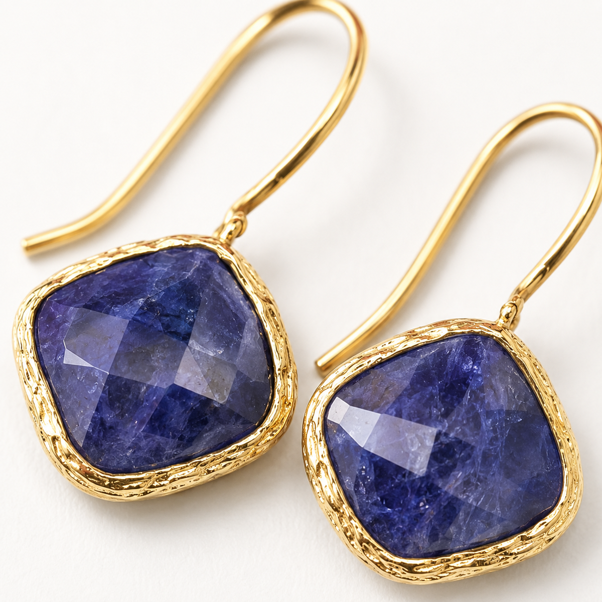 Close view of blue sapphire stones set in gold-plated earrings.