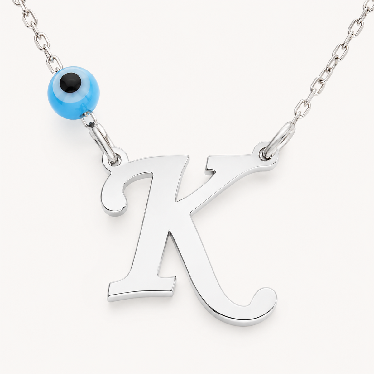Close view of the initial pendant and evil eye accent on the necklace.