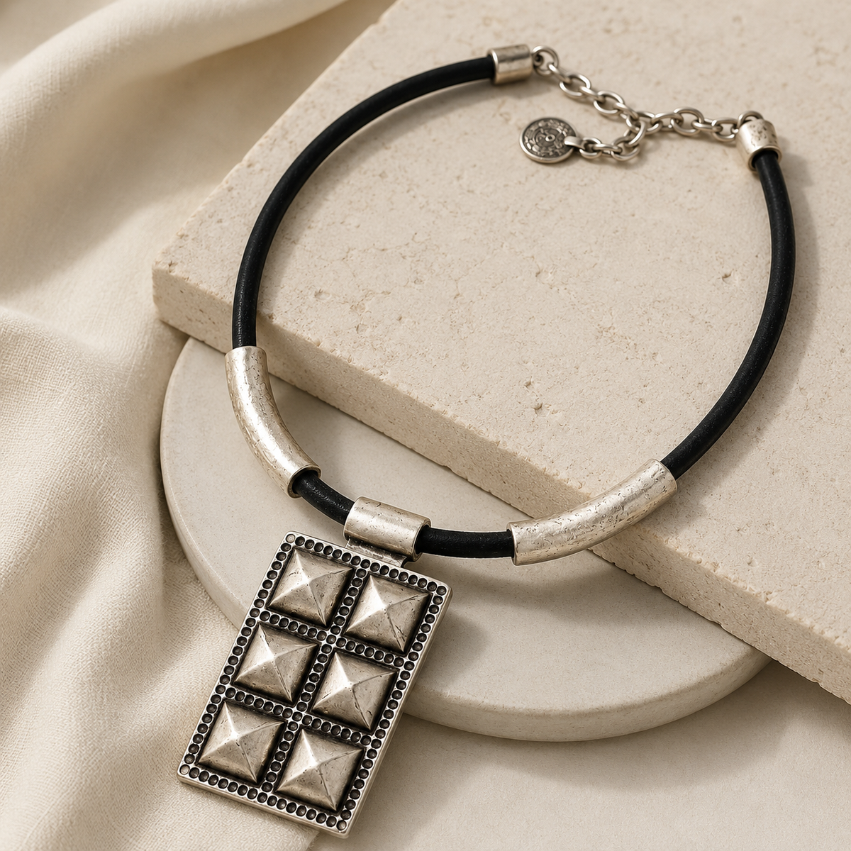 Angled view of a black cord geometric pendant necklace with silver-tone accents.