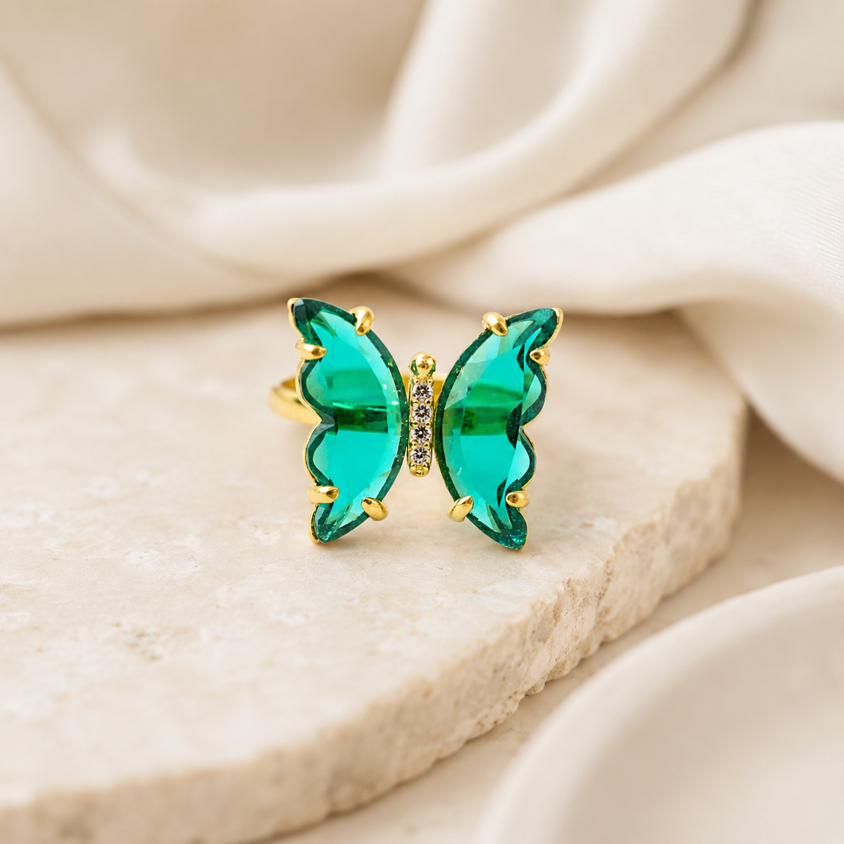Gold-tone butterfly ring with bright green crystal-like wings.